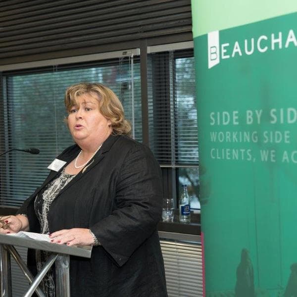 Partner and chair of Beauchamps, Imelda Reynolds, welcoming guests to the event at podium with Beauchamps pull up banner behind her